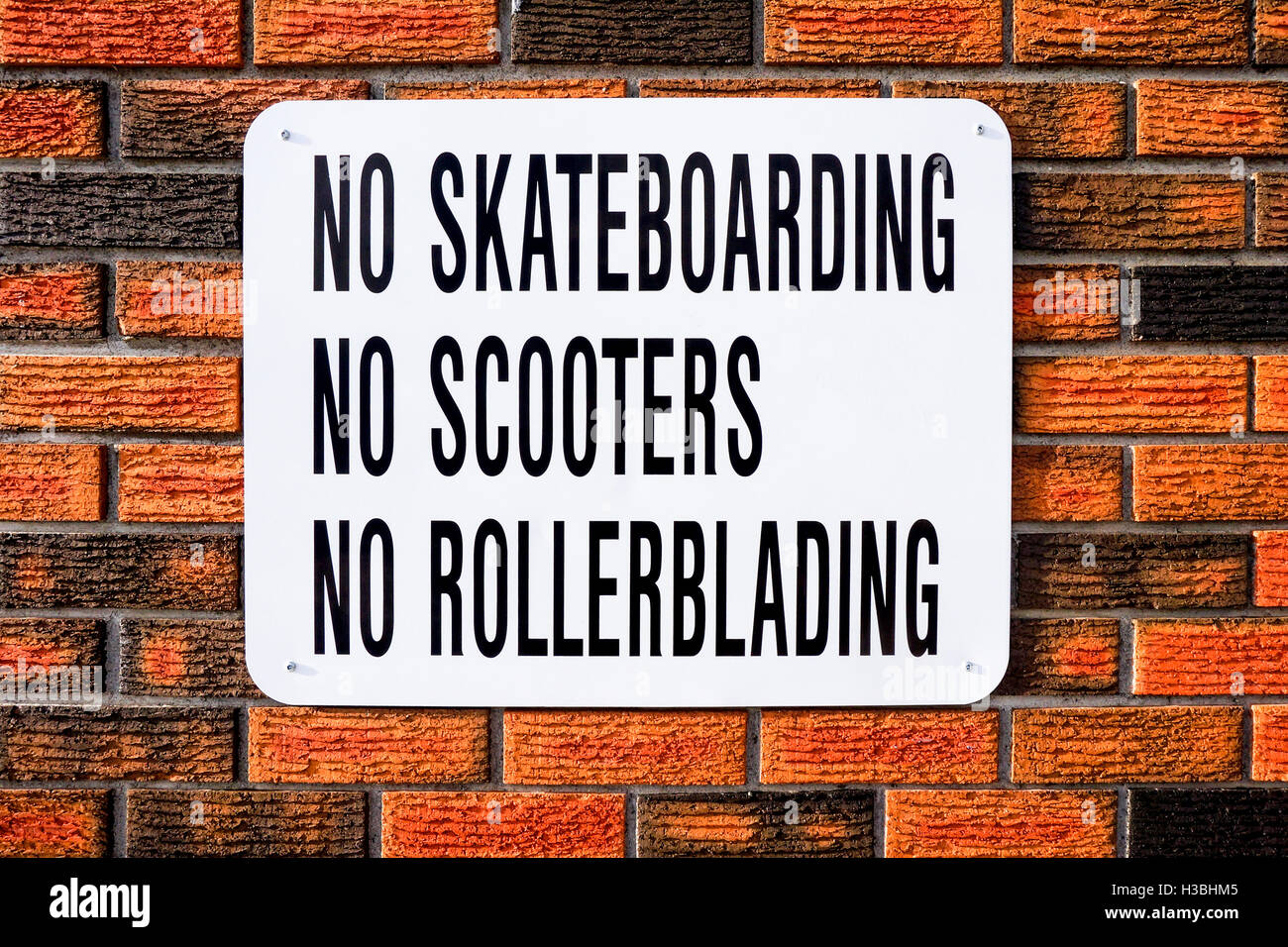 No skateboarding, no scooters, no rollerblading sign on red brick wall