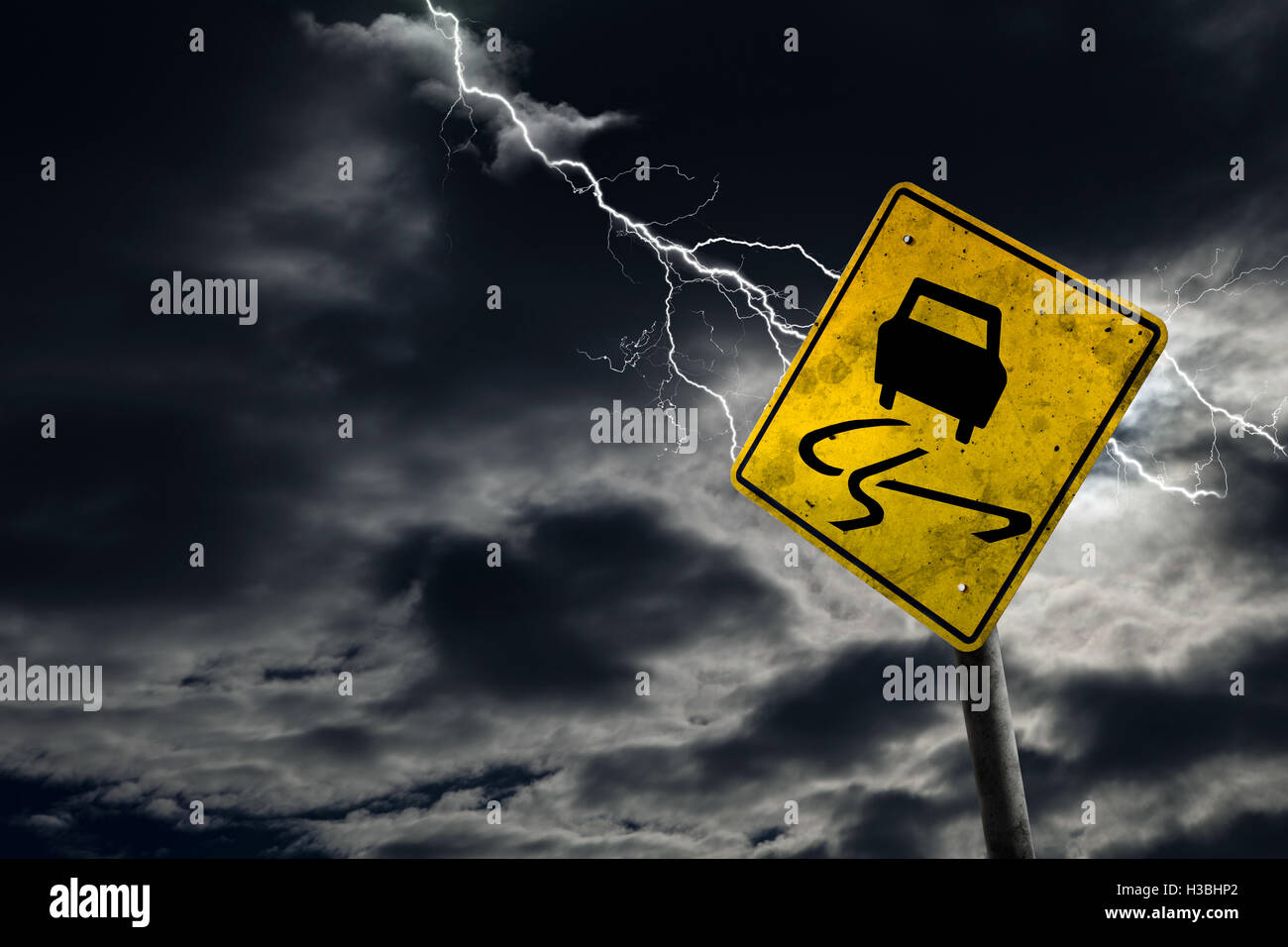 Slippery when wet road sign against a stormy background with lightning