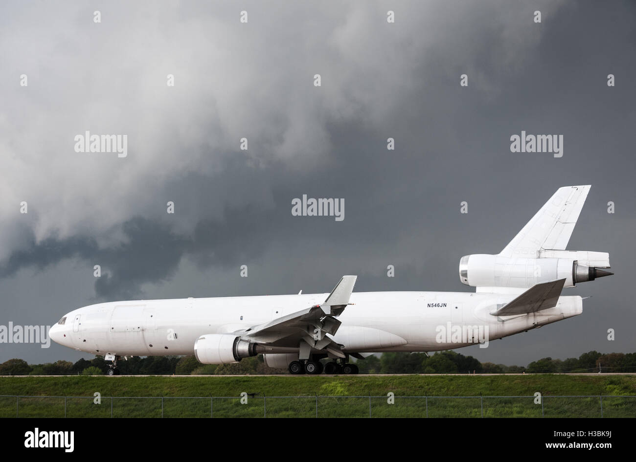 White air-cargo commercial jet sunlit against a dark stormy sky at Memphis International Airport in Memphis, Tennessee. (USA) Stock Photo