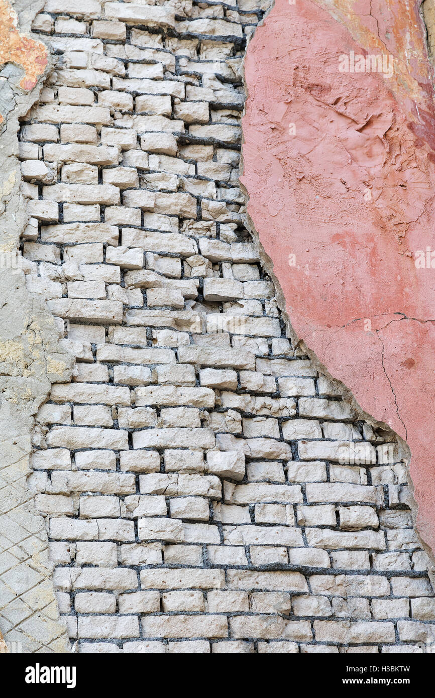 Damaged brick wall with a piece of plaster Stock Photo