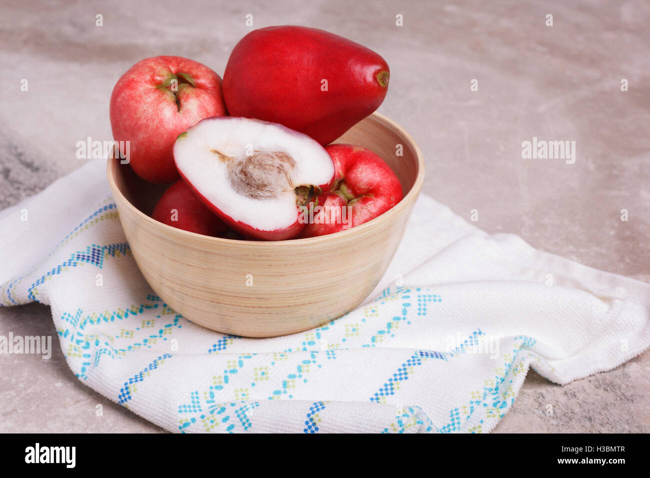 Tropical fruit Acmella oleracea (toothache plant, paracress, electric daisy, jambu) in wooden bowl on marble table. Stock Photo