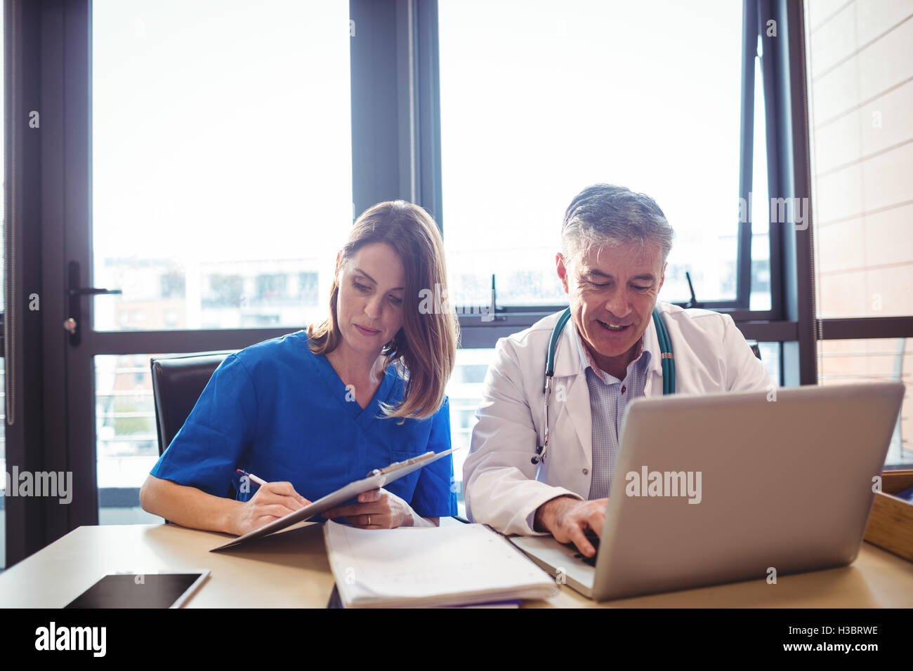 Doctor discussing with nurse over laptop Stock Photo