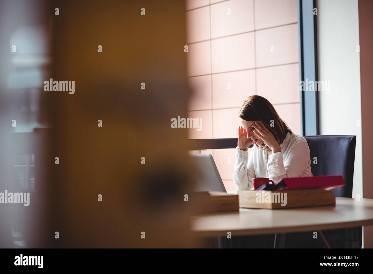 Stressed woman sitting at her desk Stock Photo
