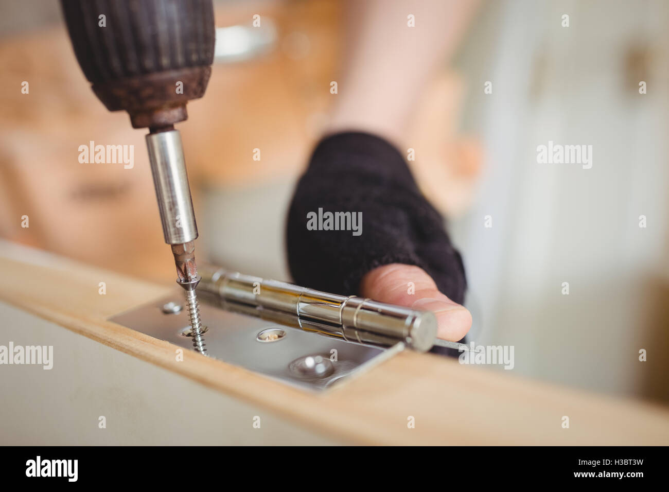 Carpenter tightening screw to hinges on a wooden door Stock Photo Alamy