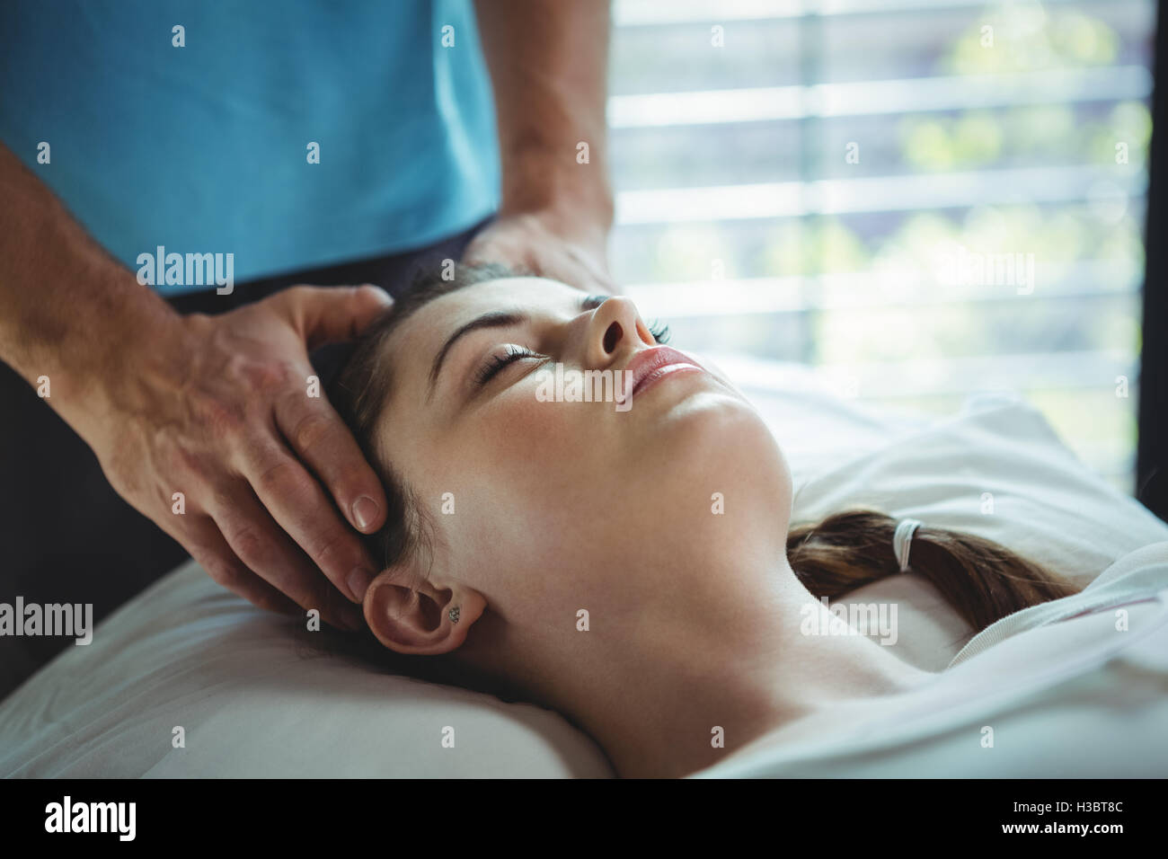 Male physiotherapist giving head massage to female patient Stock Photo