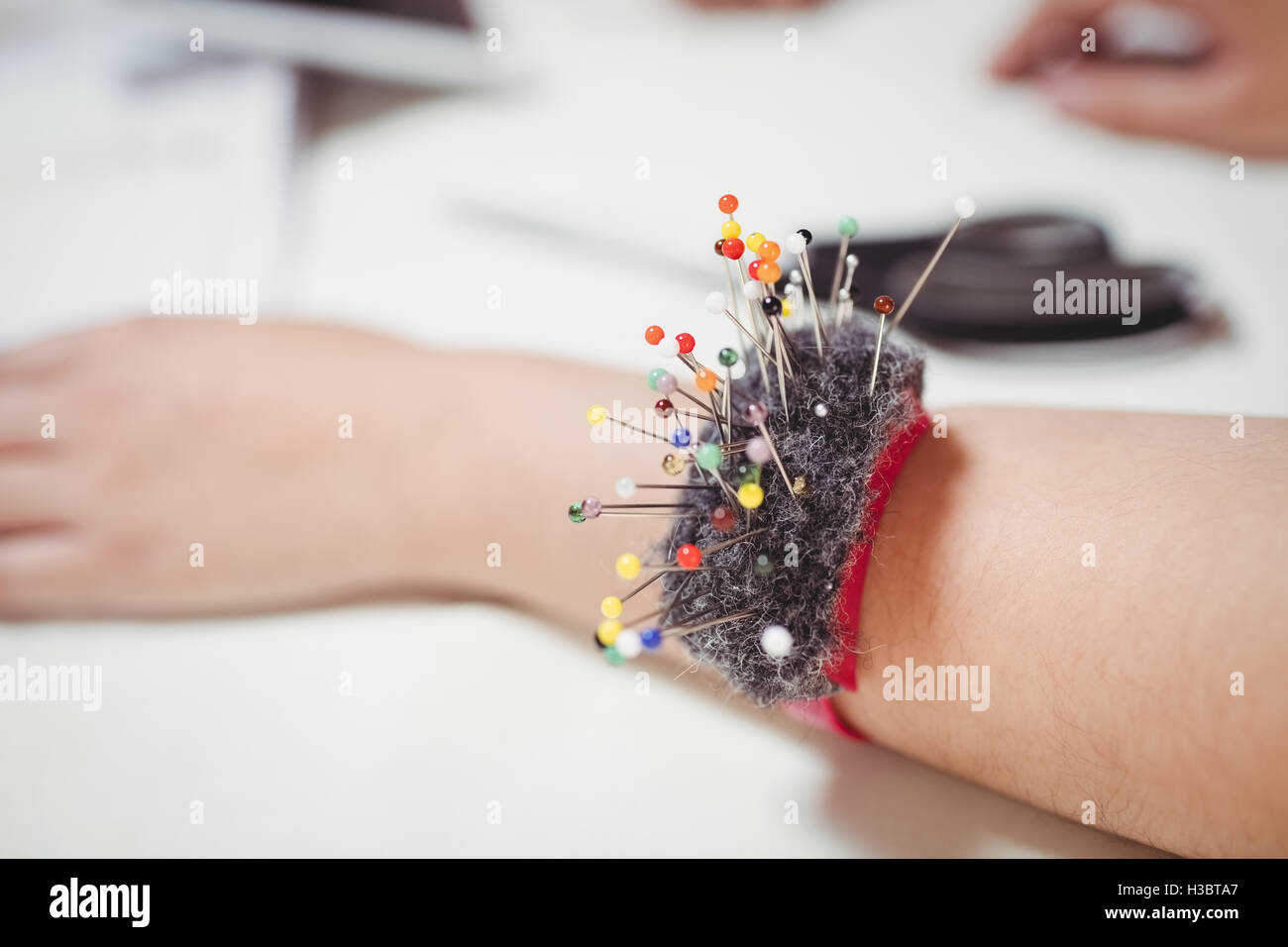 Pincushion on fashion designer wrist in the studio Stock Photo Alamy