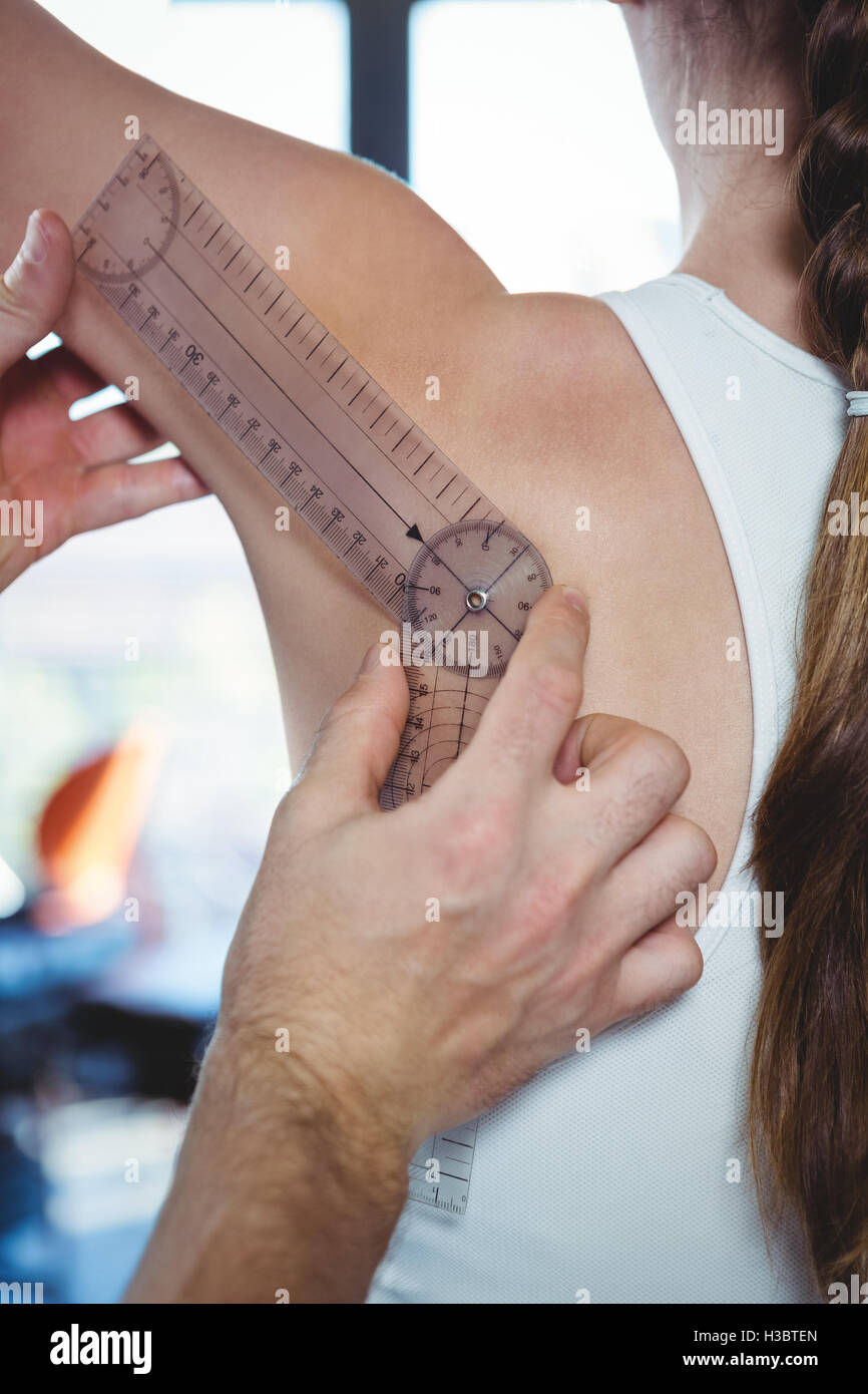 Physiotherapist examining female patient's shoulder with goniometer Stock Photo
