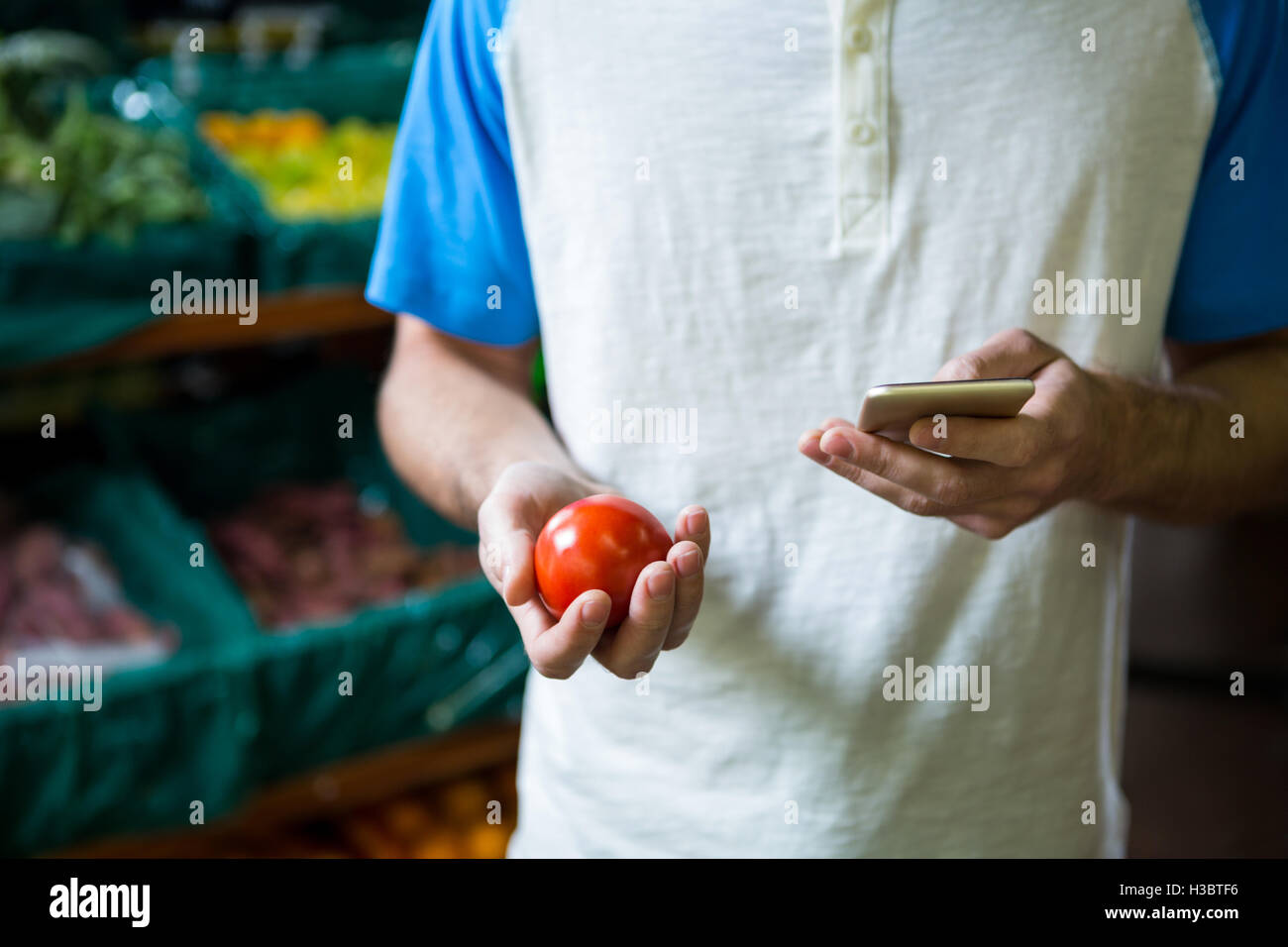 Man holding tomato and using phone Stock Photo