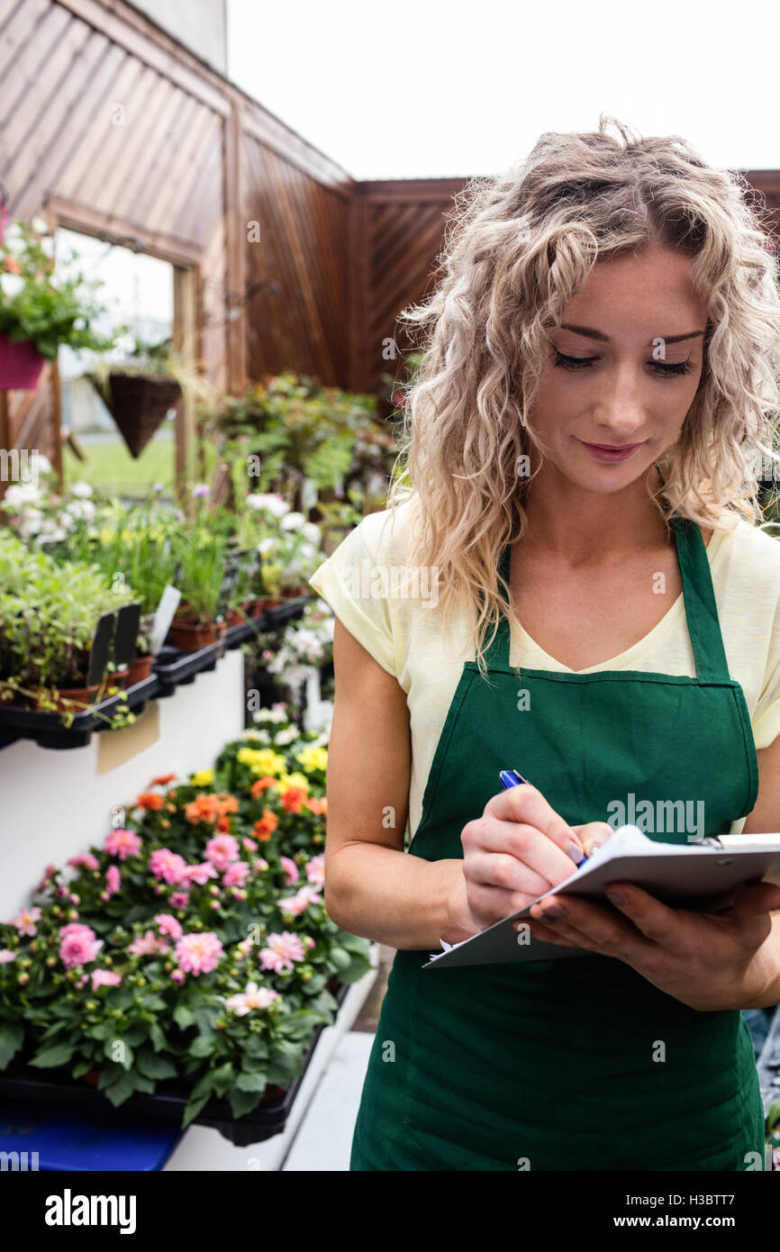 Female florist writing on clipboard Stock Photo Alamy