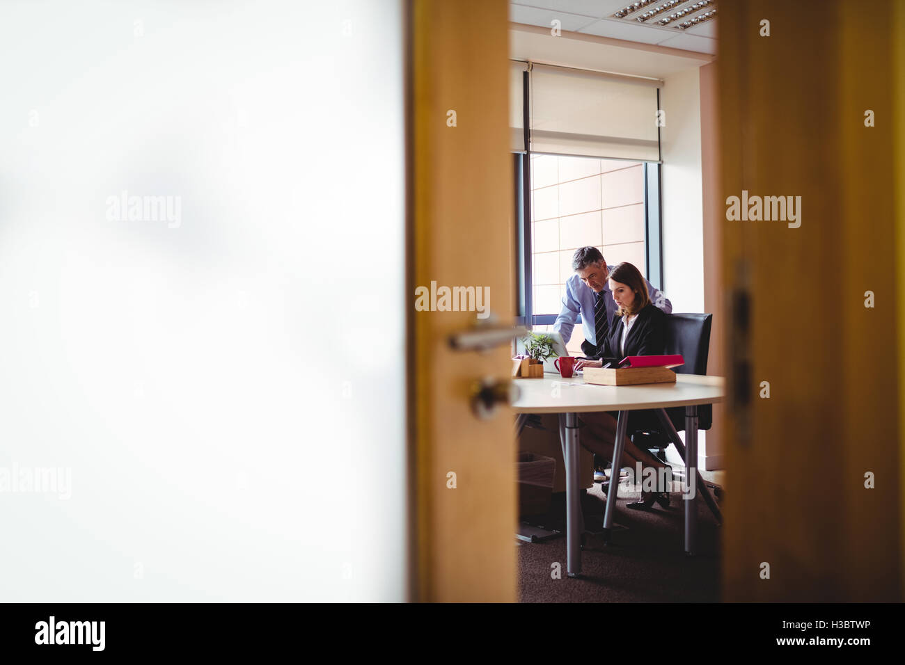 Businessman discussing with colleague over laptop Stock Photo