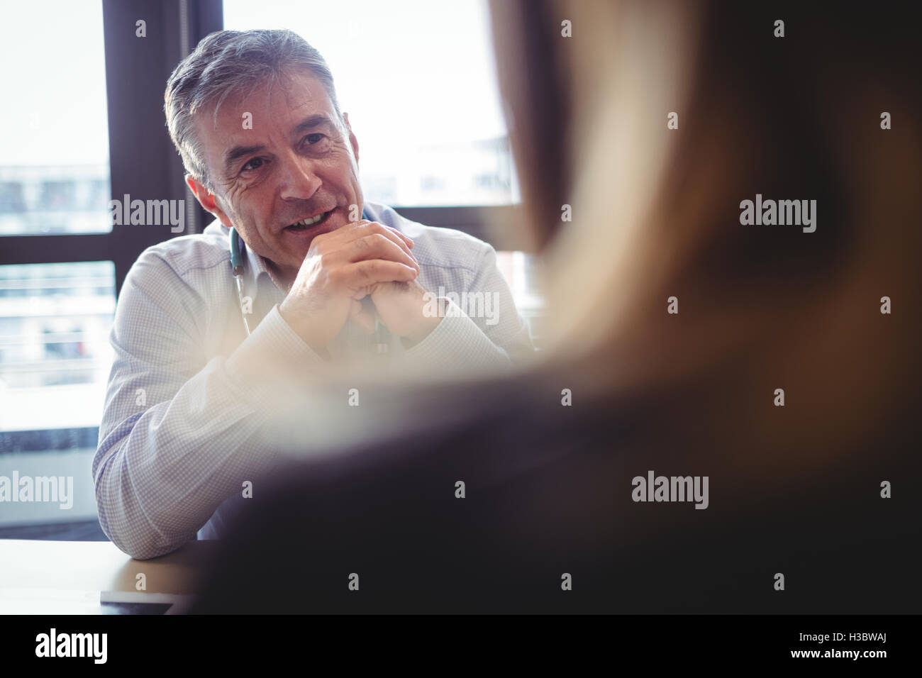 Mature smiling doctor sitting hi-res stock photography and images - Alamy