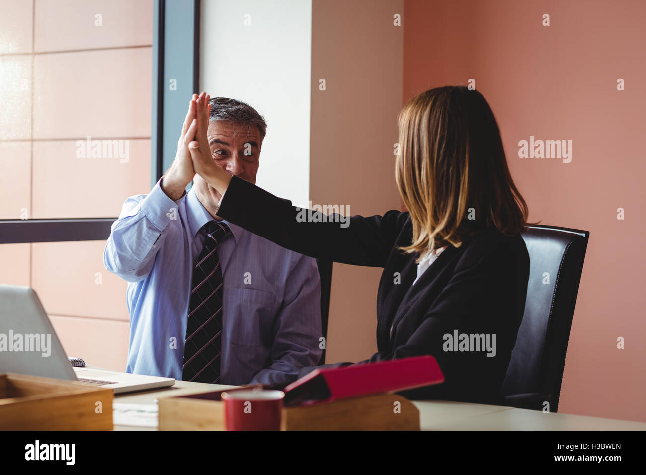 Businessman and businesswoman giving a high five Stock Photo