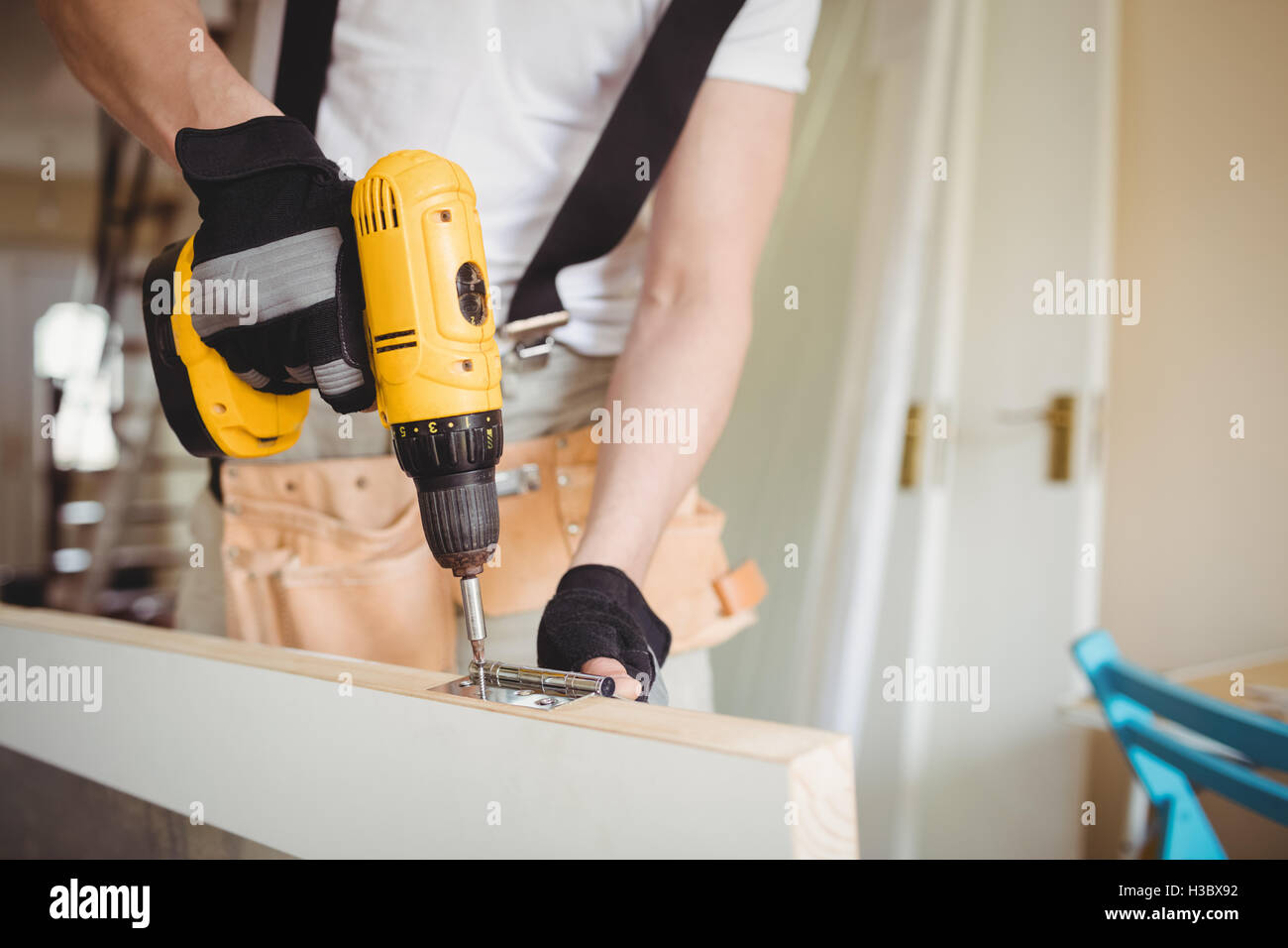 Carpenter tightening screw to hinges on a wooden door Stock Photo Alamy