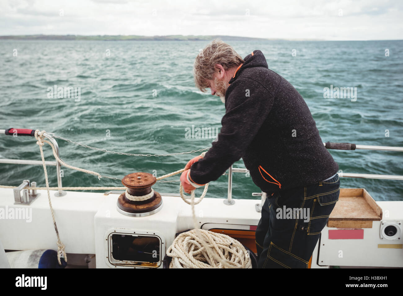 Fisherman tying rope on bollard Stock Photo