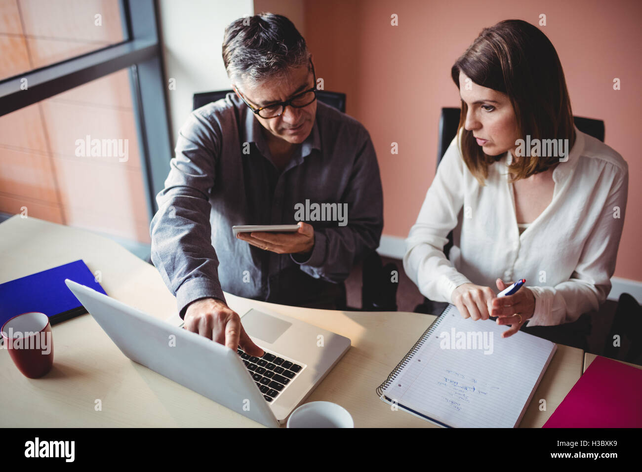 Man and woman discussing over digital tablet and laptop Stock Photo