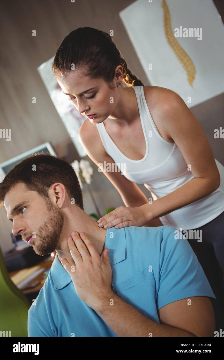 Female physiotherapist examining neck of a male patient Stock Photo