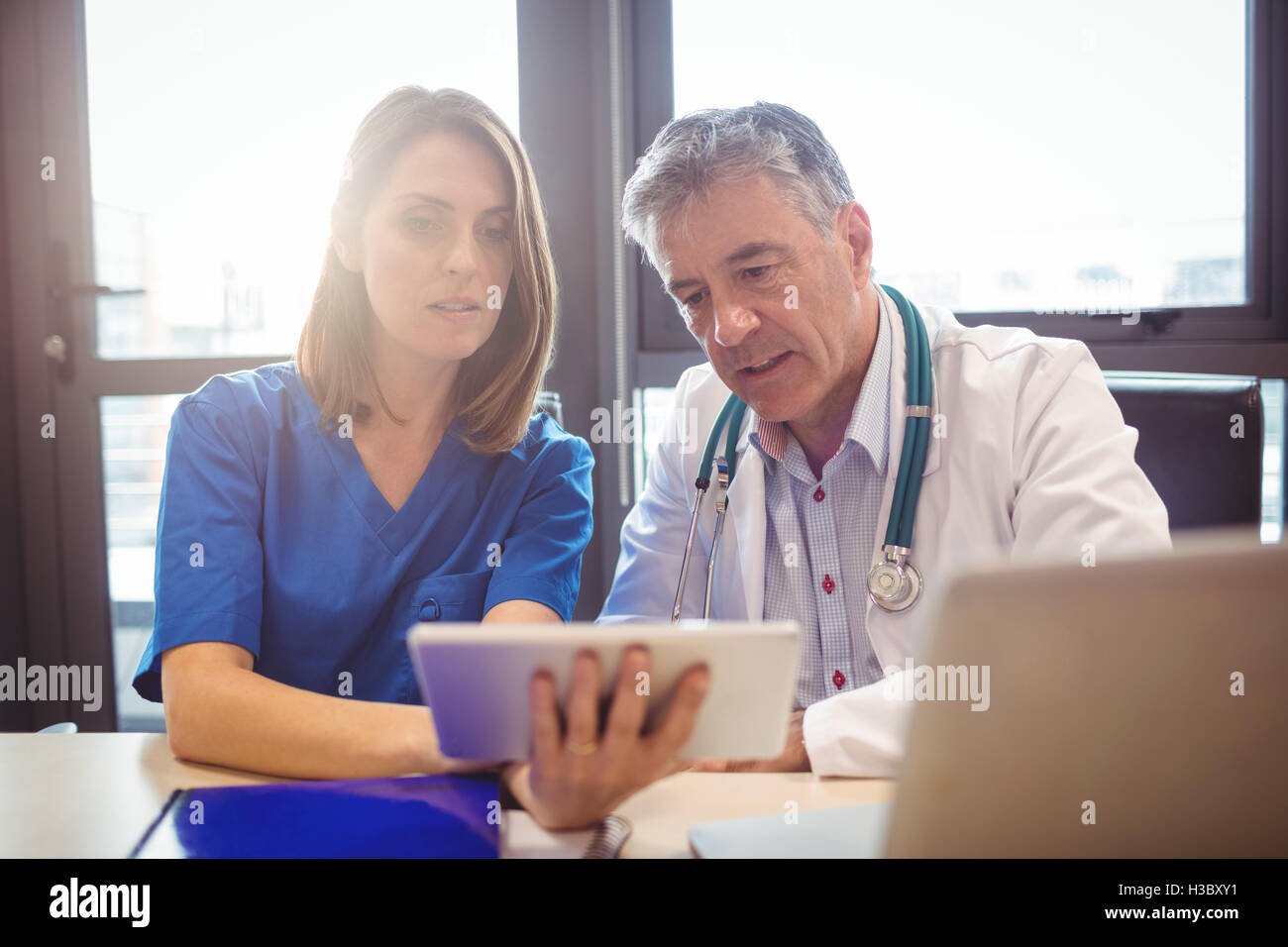 Doctor discussing with nurse over digital tablet Stock Photo