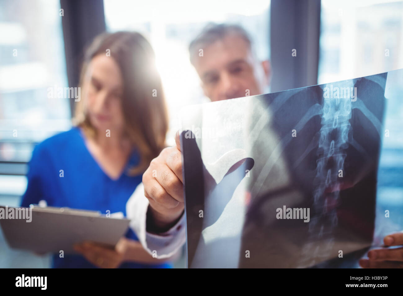 Doctor examining x-ray while nurse writing on clipboard Stock Photo