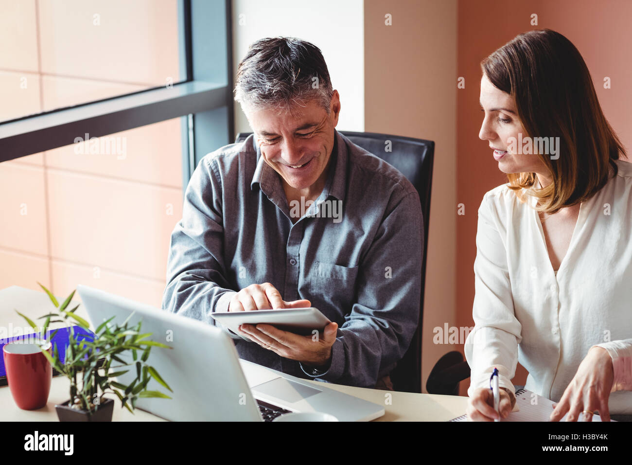 Man and woman discussing over digital tablet Stock Photo