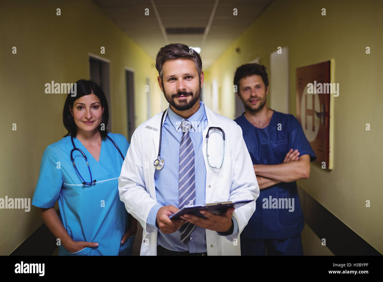 Portrait of doctor standing with nurse and ward boy in corridor Stock Photo