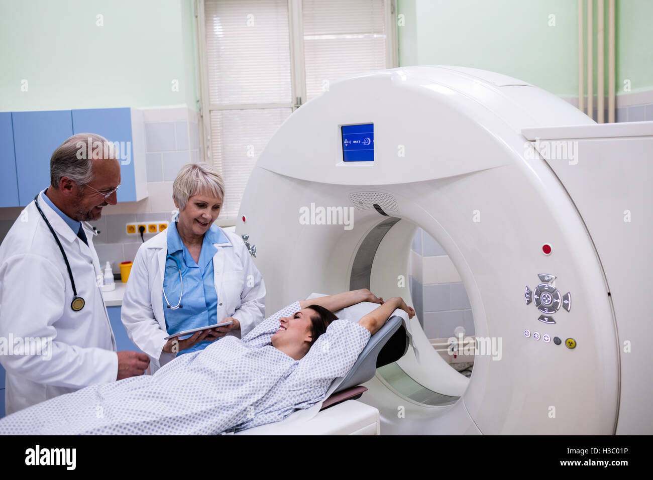 Doctors interacting with patient in scanning room Stock Photo