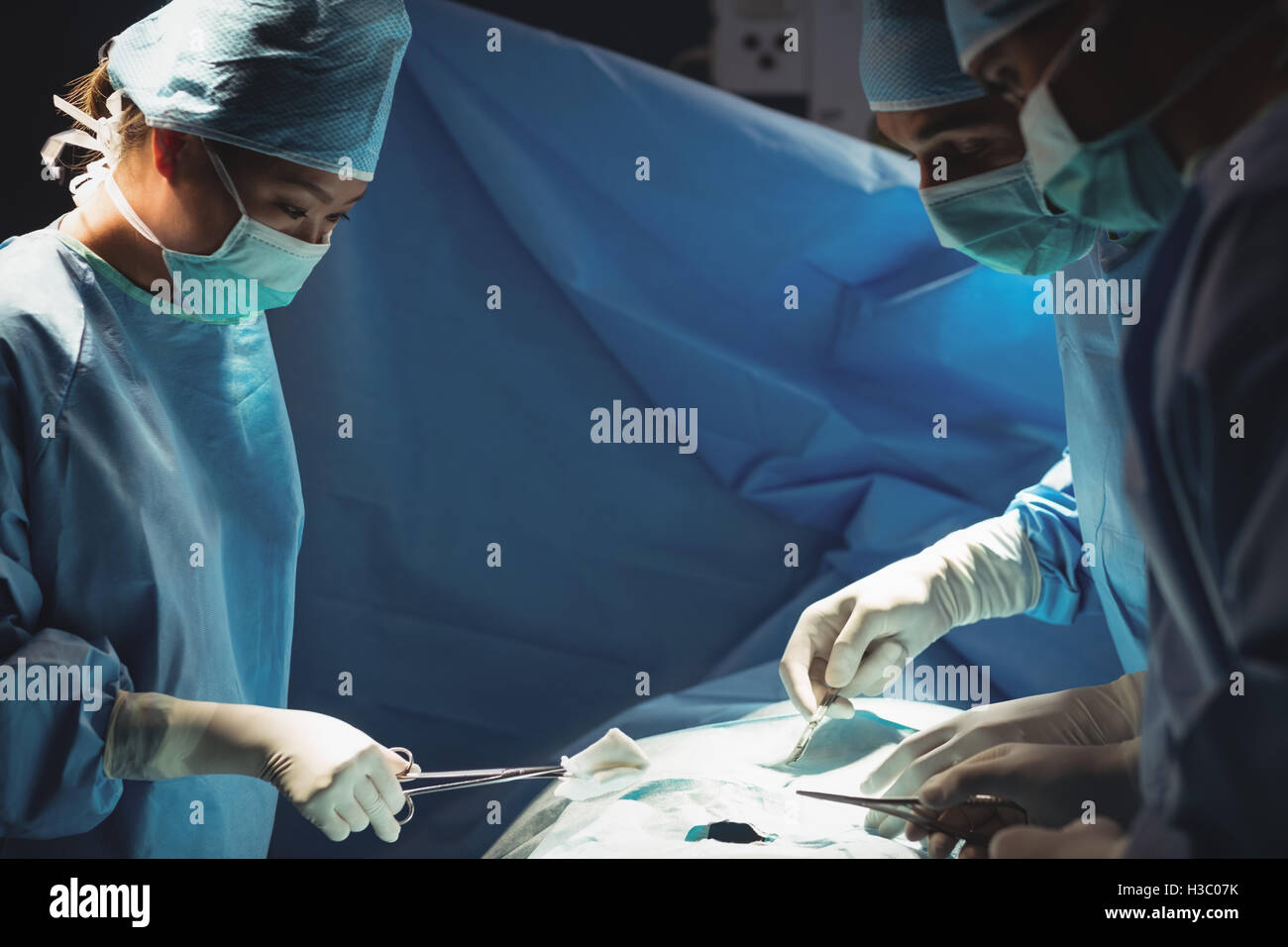 Surgeons performing operation in operation room Stock Photo