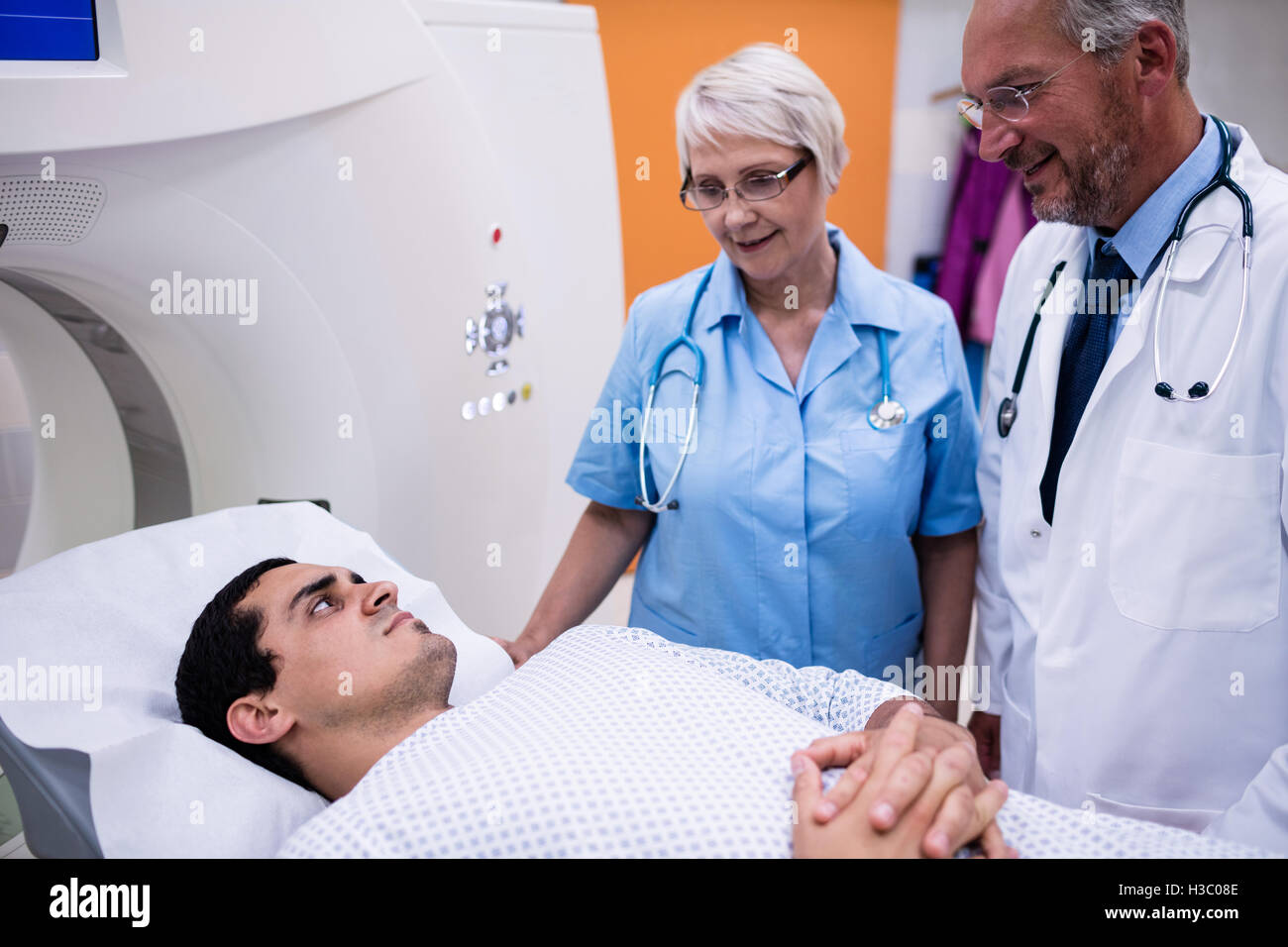 Doctors interacting with patient in scanning room Stock Photo