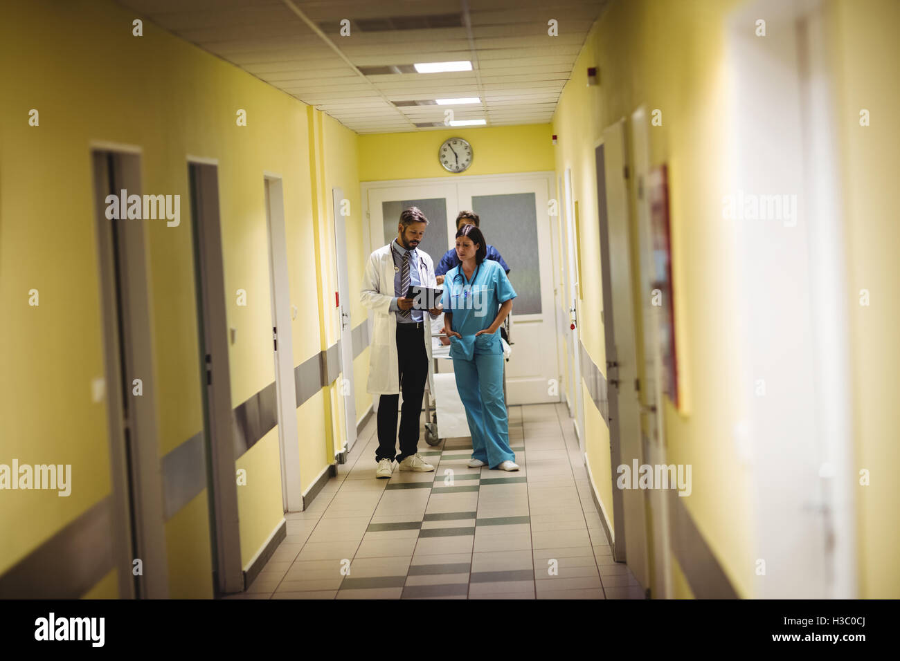 Male doctor and nurse interacting over a report in corridor Stock Photo