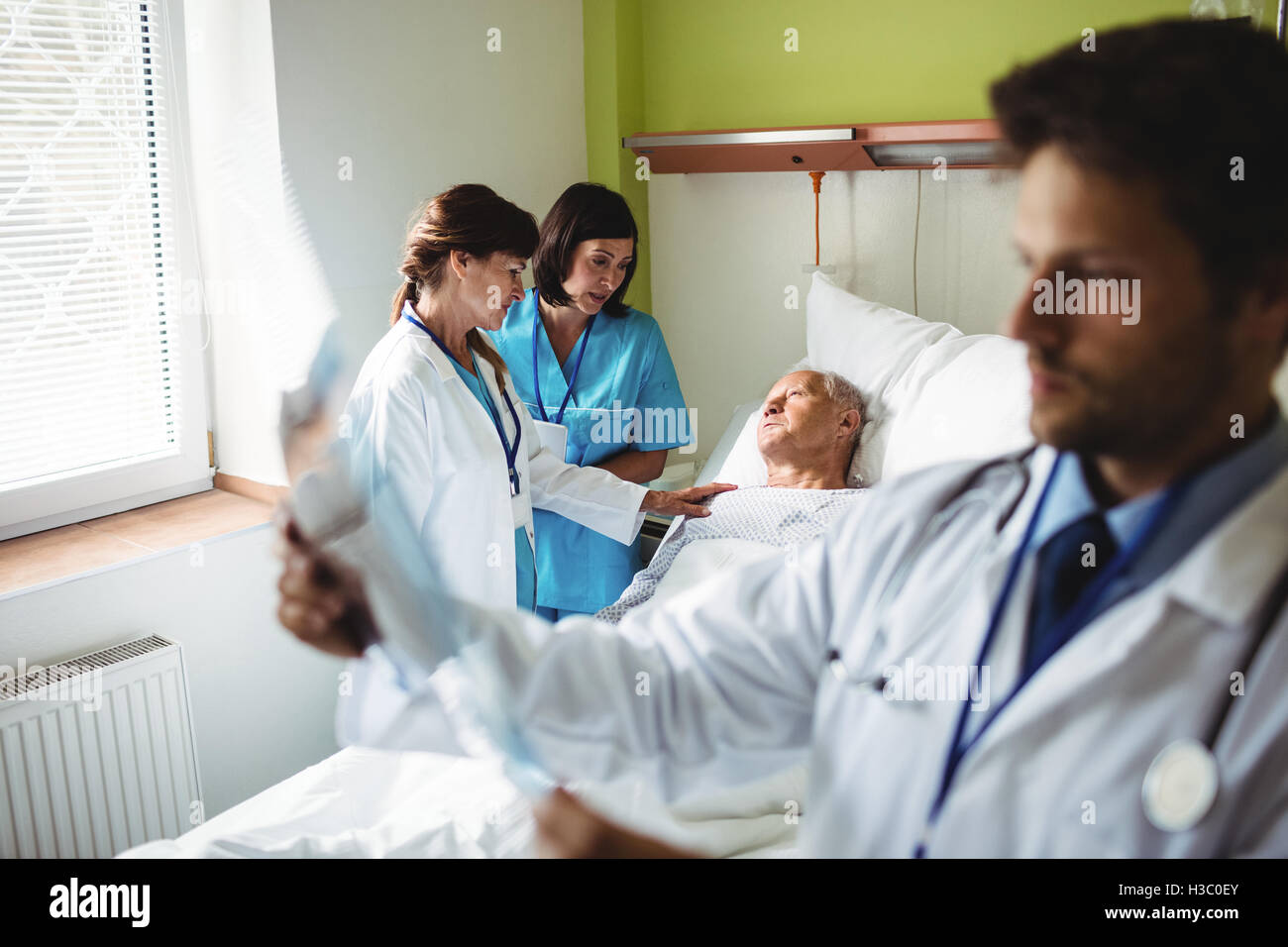 Female doctor consoling senior patient with nurse Stock Photo
