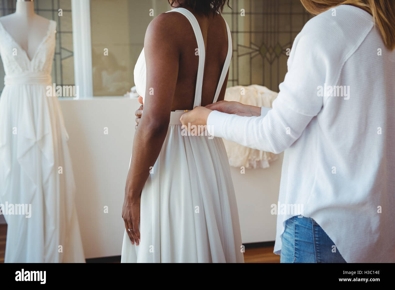 Woman trying on wedding dress with the assistance of fashion designer Stock Photo