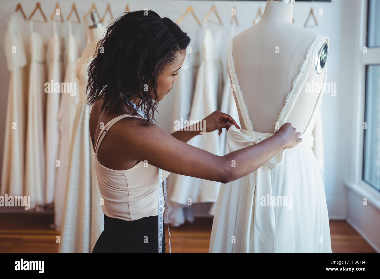 Female fashion designer adjusting the dress on mannequin Stock Photo