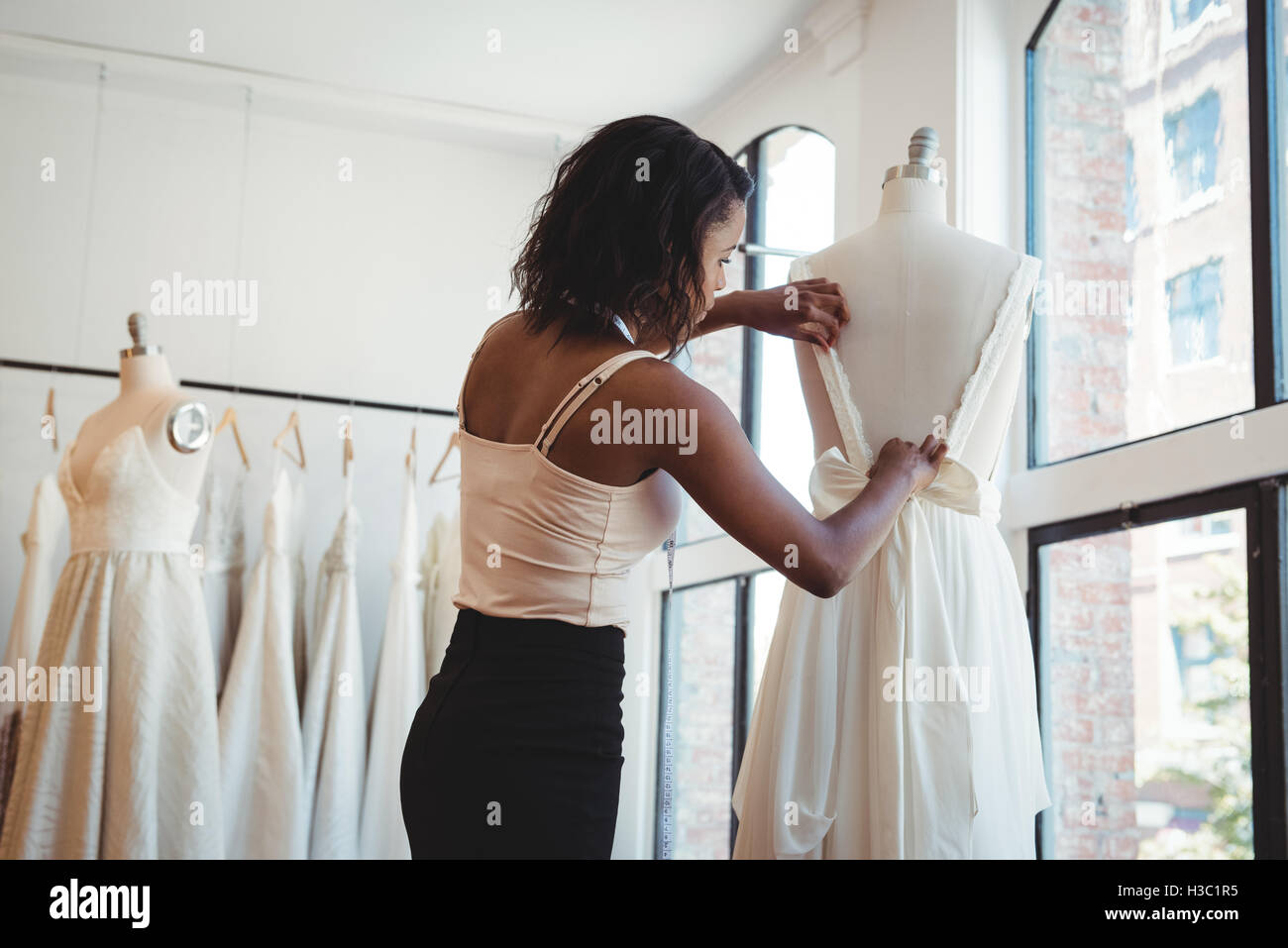 Female fashion designer adjusting the dress on mannequin Stock Photo ...