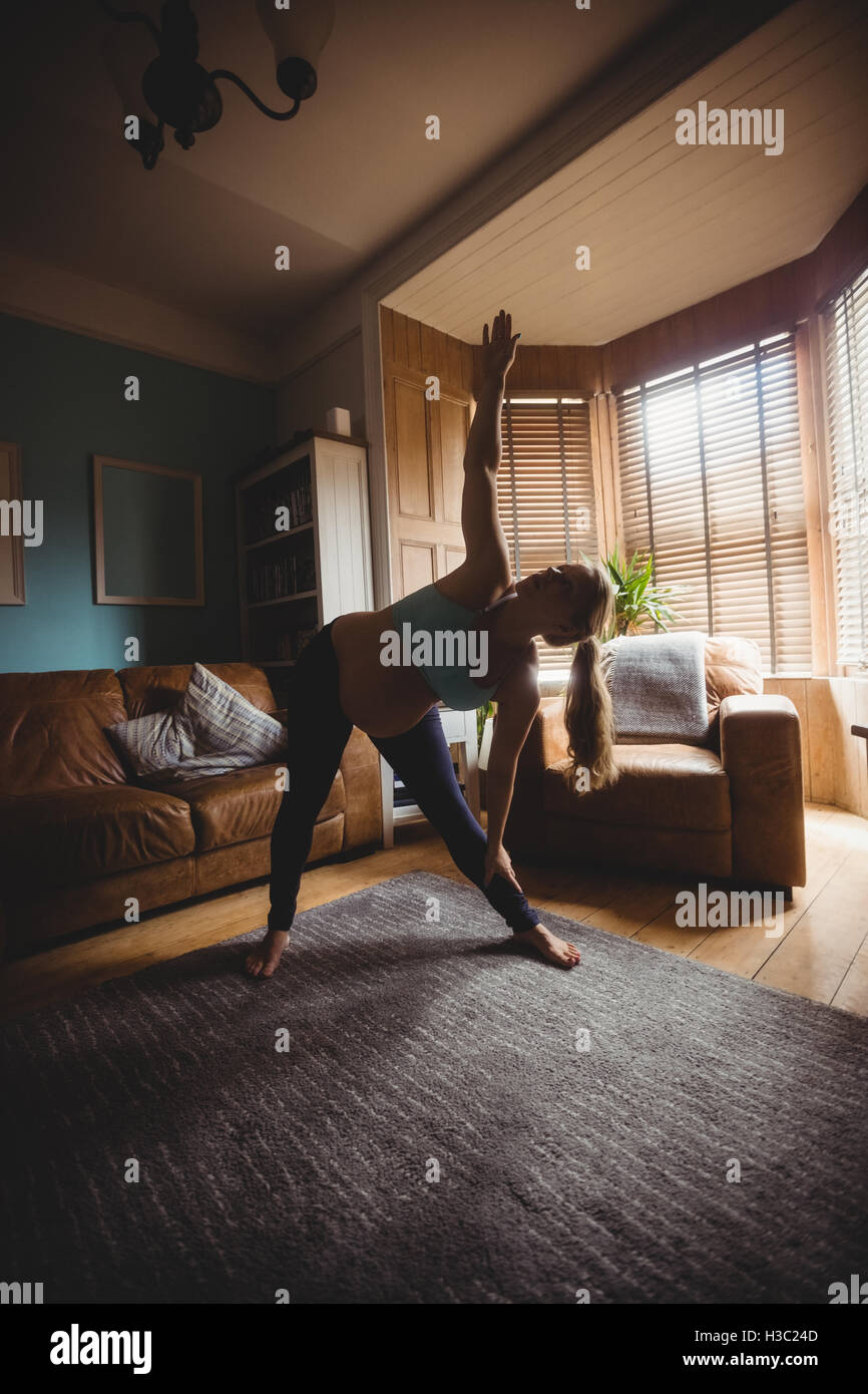 Pregnant woman performing stretching exercise in living room Stock ...