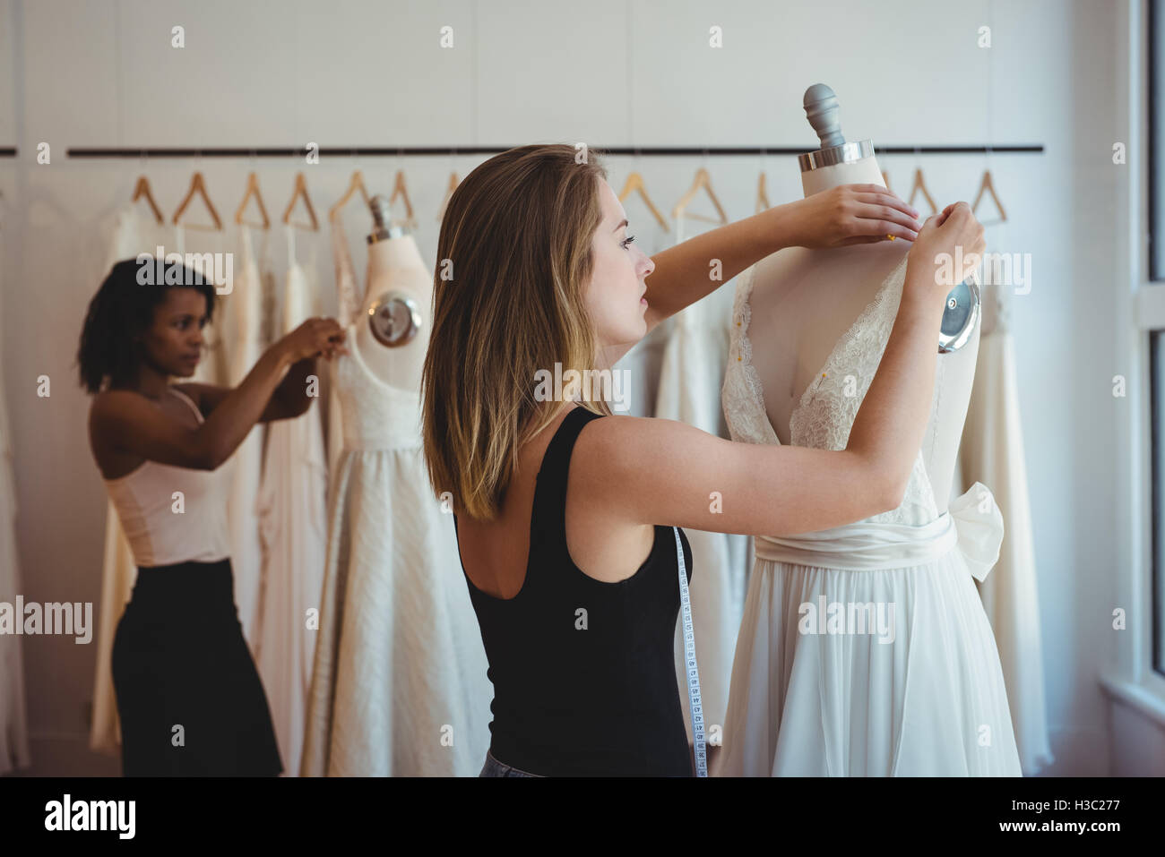 Female fashion designers adjusting the dress on mannequin Stock Photo ...