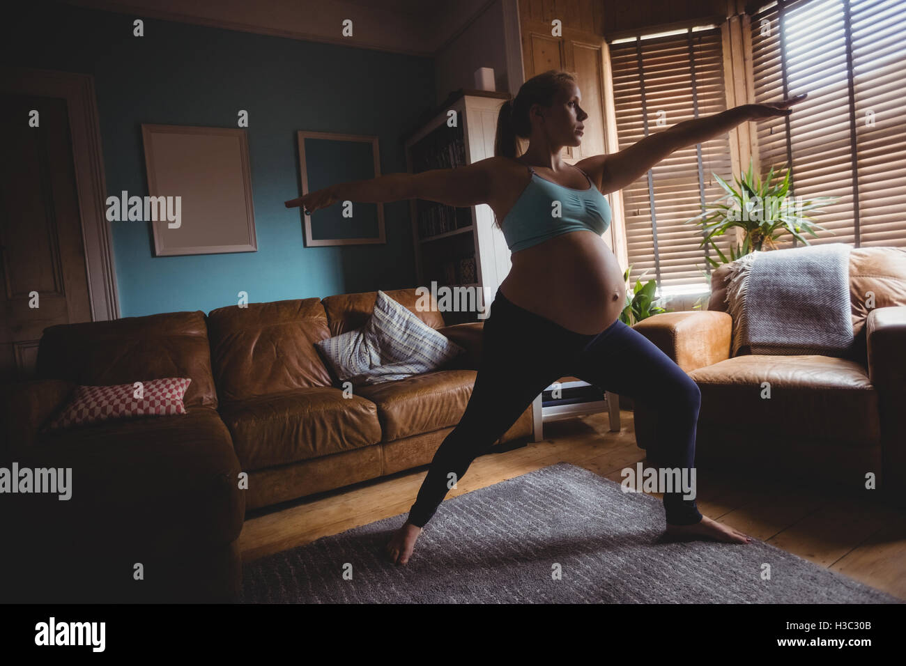 Pregnant woman performing stretching exercise in living room Stock ...