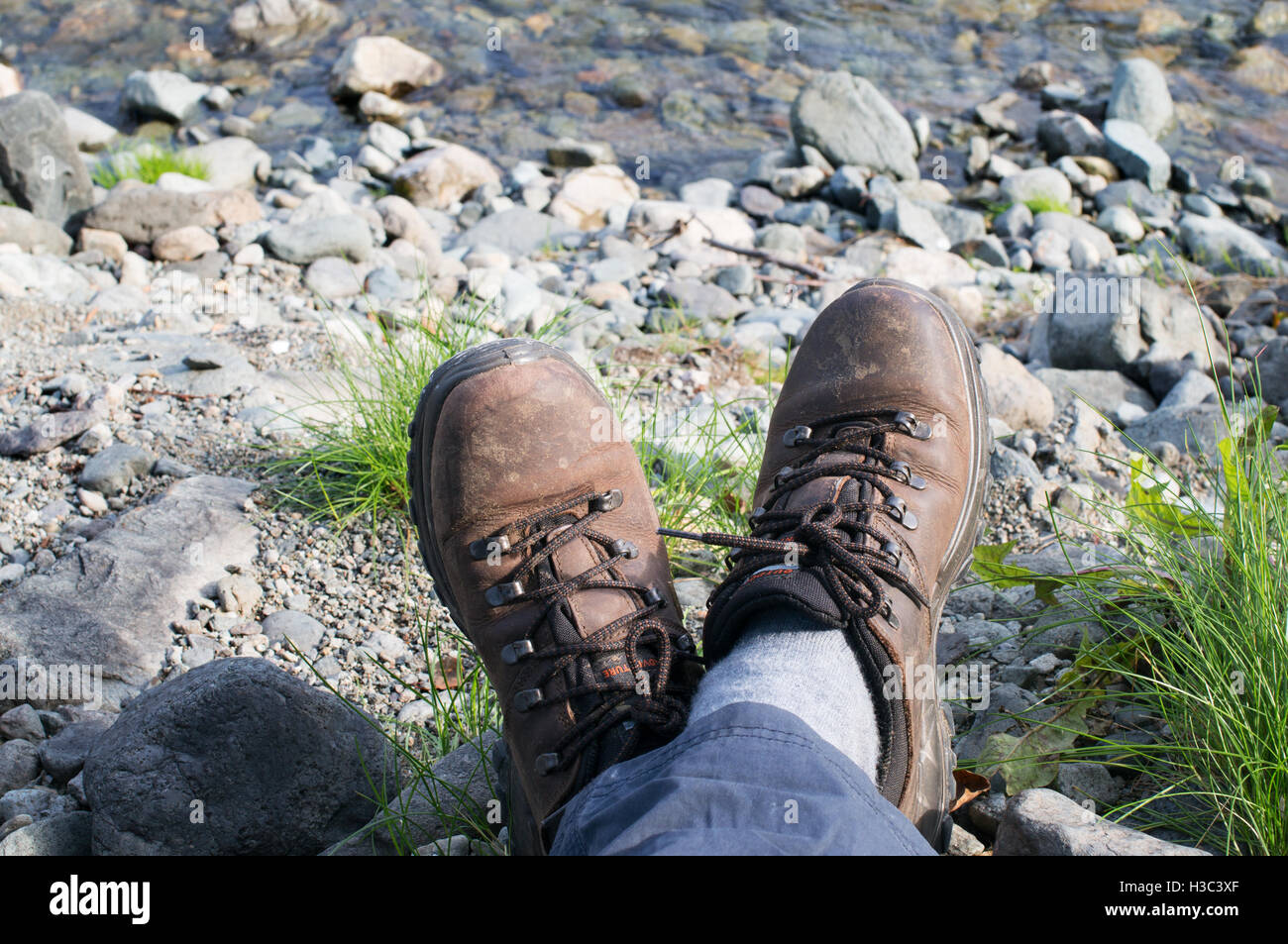 Feet and boots of walker resting near stream in the Lake District England, UK Stock Photo