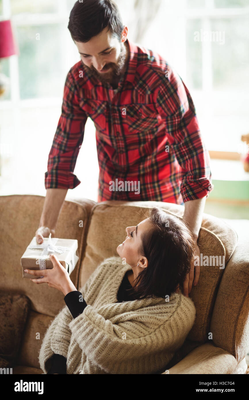 Man surprising woman with a gift in living room Stock Photo