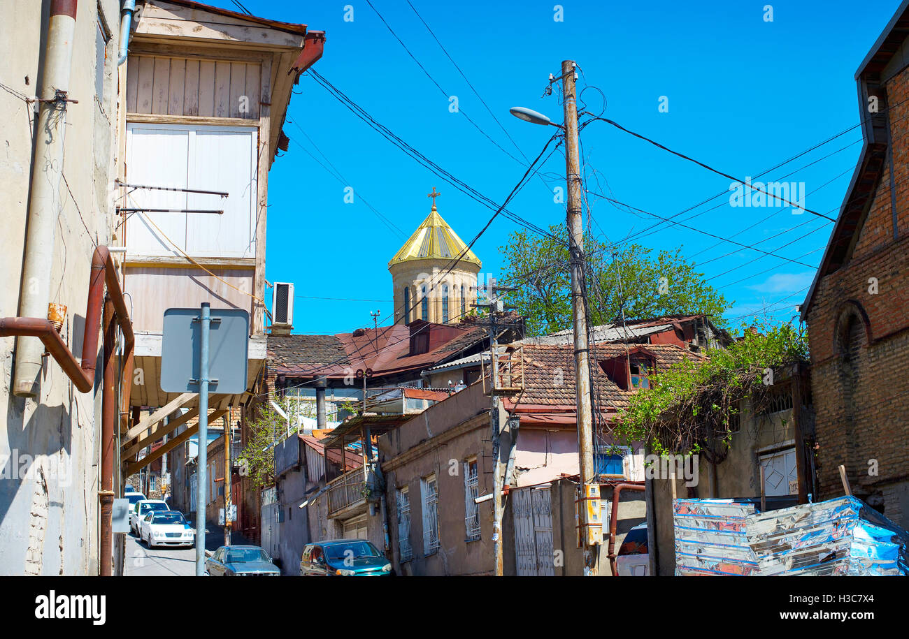 Street in the Tbilisi slum. Dome of Sameba cathedral on the background. Georgia Stock Photo