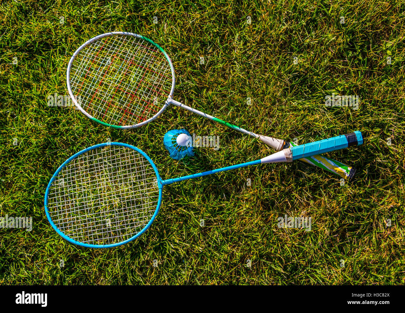 Shuttlecock and badminton rackets outdoor on green grass Stock Photo