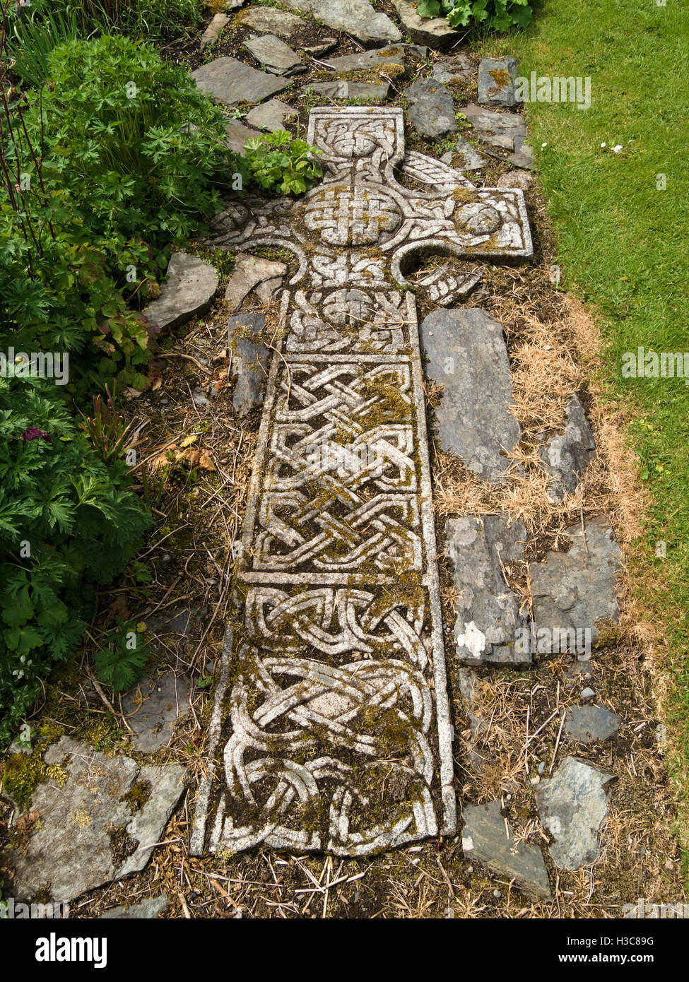 Old Celtic Cross laid flat and buried to form ornate garden path feature, Colonsay House Gardens, Isle of Colonsay, Scotland, UK Stock Photo