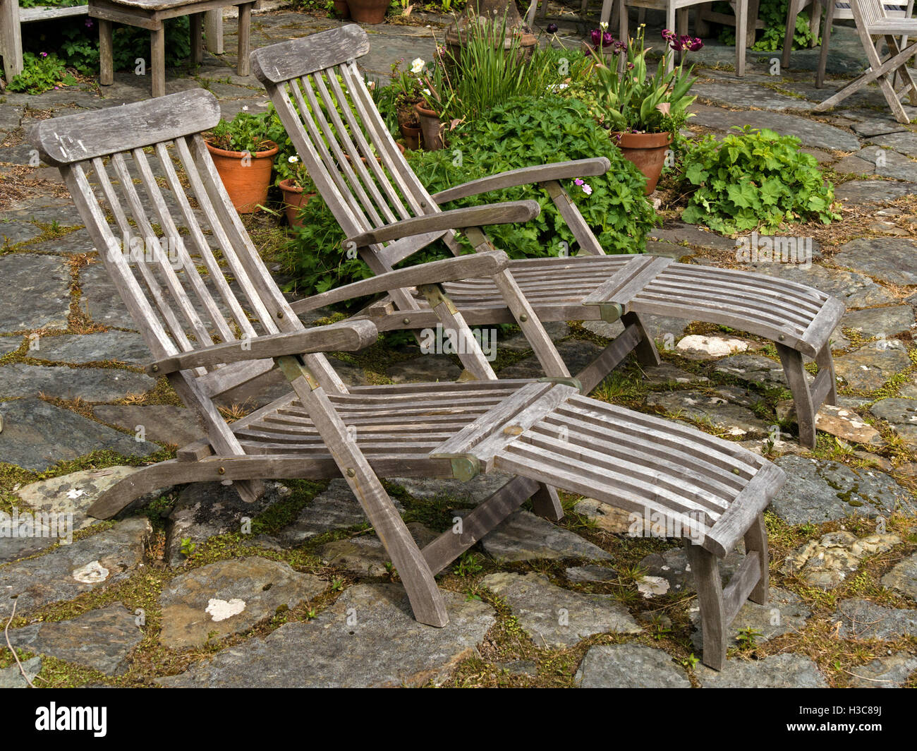 Two old wooden deck loungers on stone patio, Colonsay House Gardens, Isle of Colonsay, Scotland, UK. Stock Photo