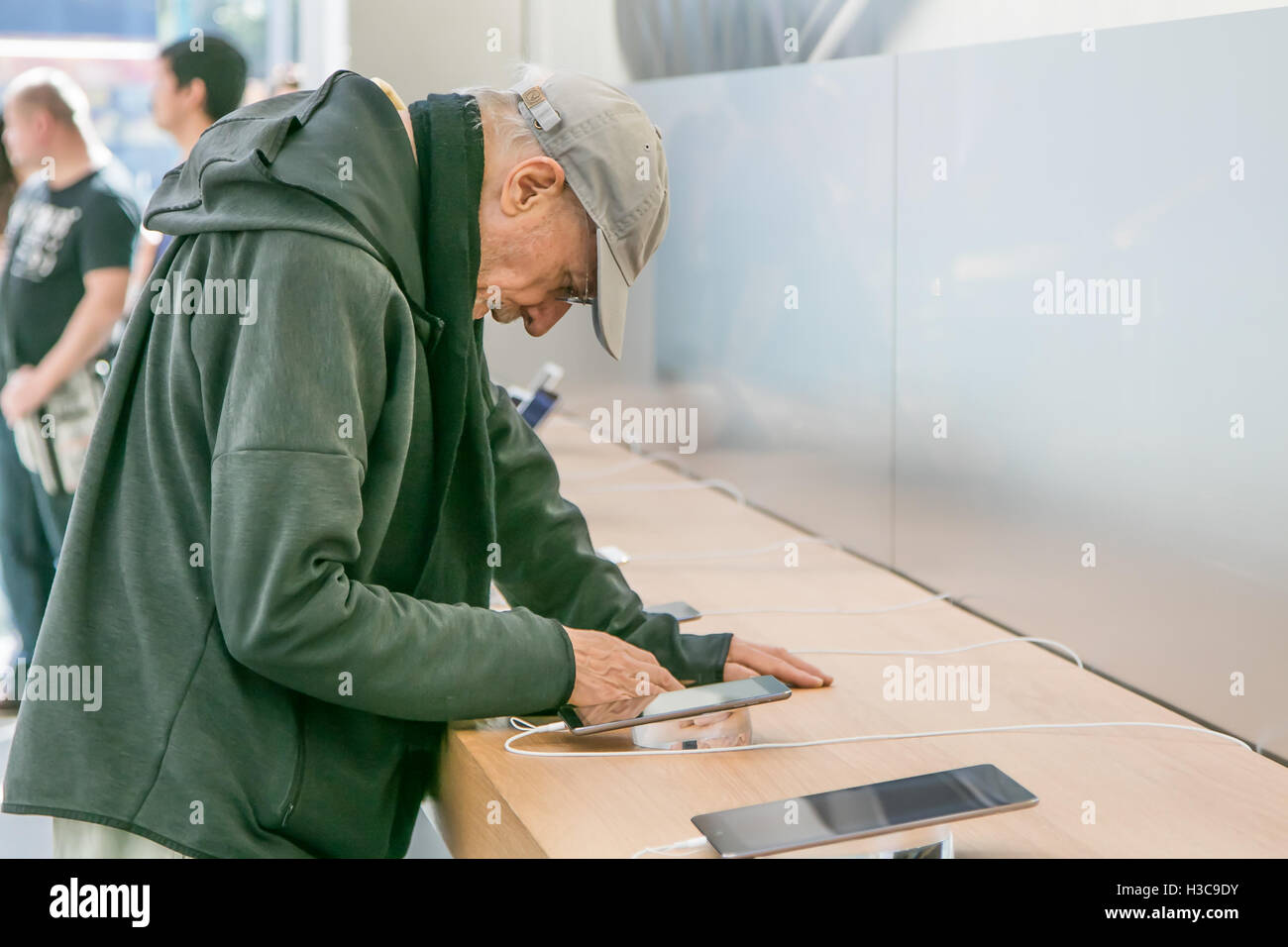 An elderly man is looking at an iPad tablet in the Apple store on Manhattan's Upper West Side. Stock Photo