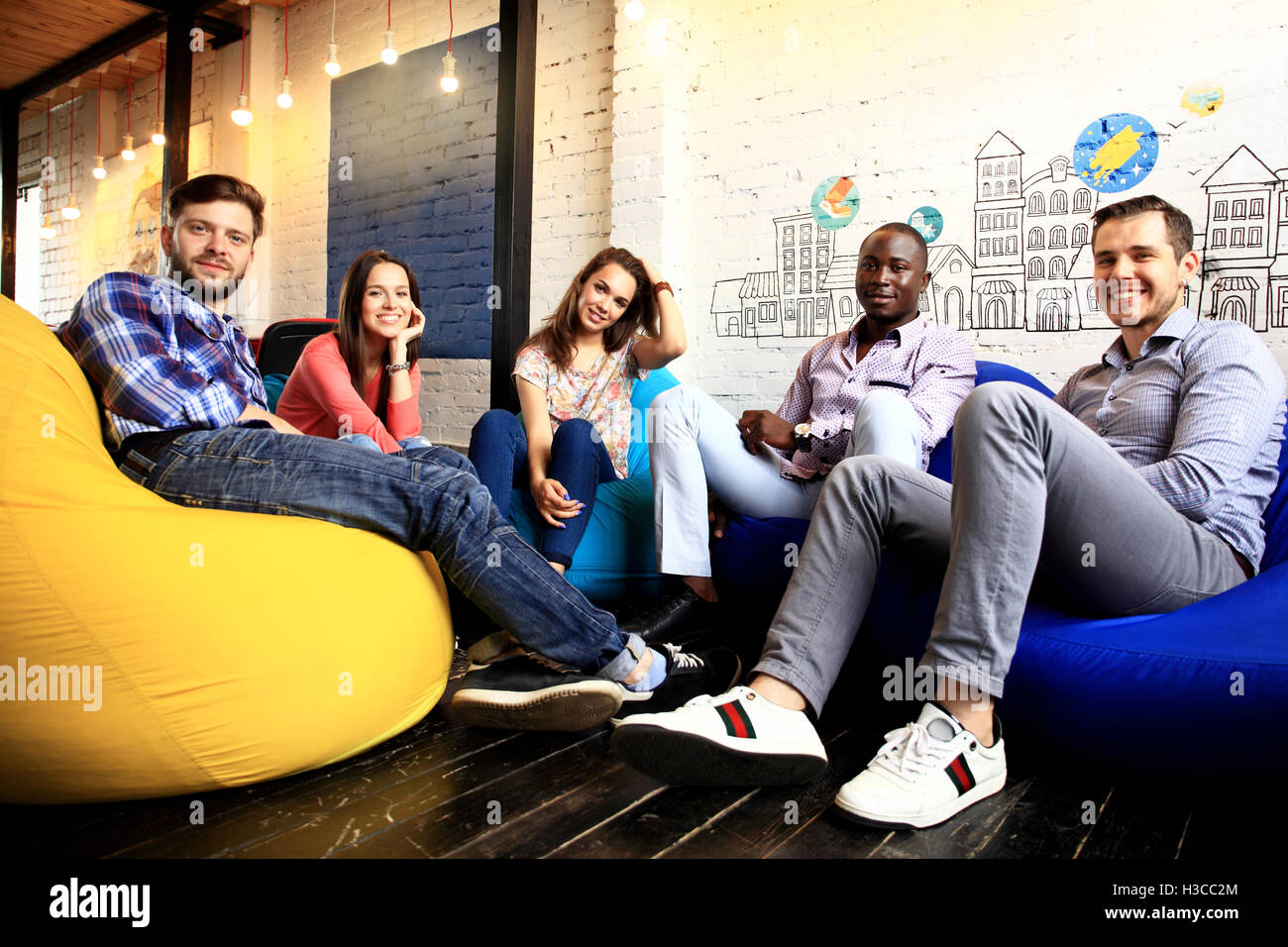 Portrait of happy young people in a meeting looking at camera and smiling. Young designers working together on a creative project Stock Photo