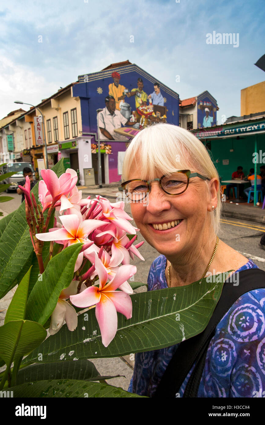 Singapore, Little India, Belilios Lane, tourist looking at red frangipani flowers on fragrant tree Stock Photo