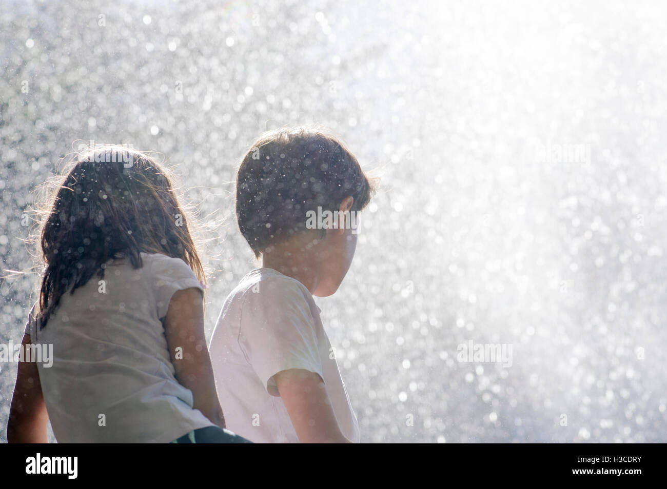 Children surrounded by spray from waterfall Stock Photo