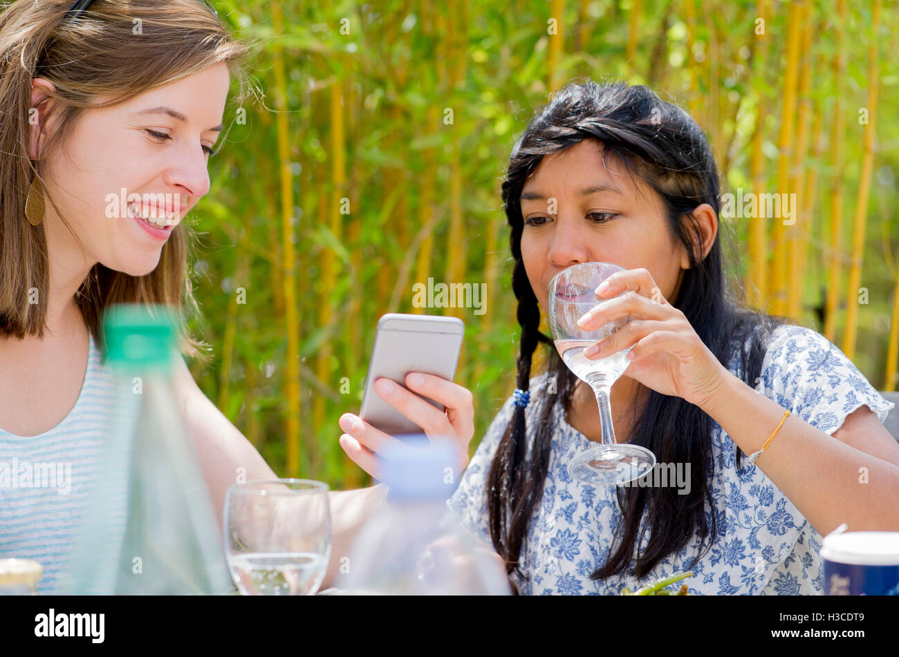 Women relaxing together outdoors, looking at smartphone Stock Photo