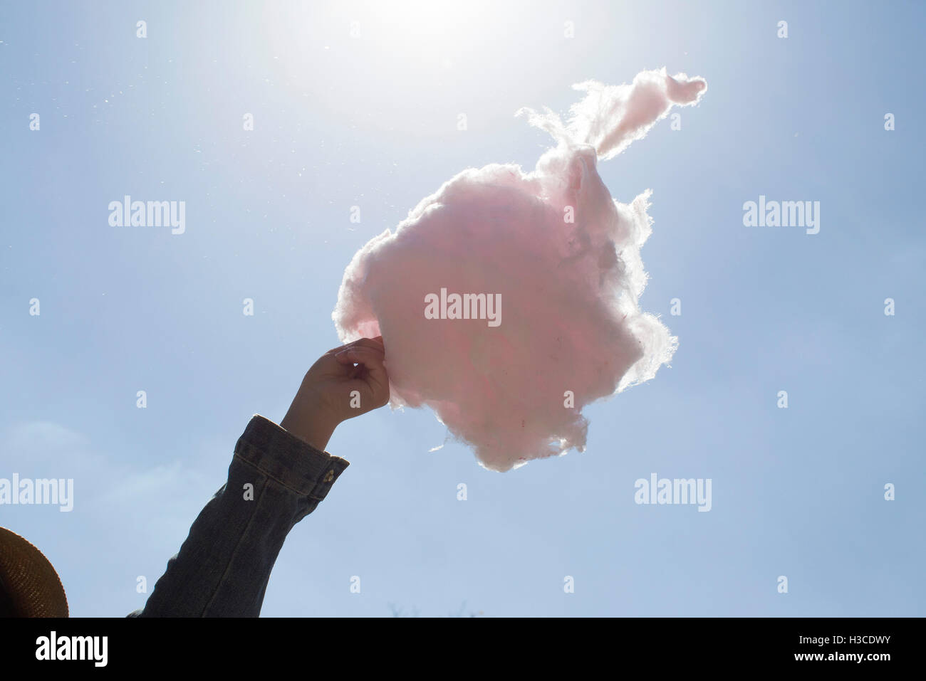 Hand holding cotton candy against blue sky Stock Photo