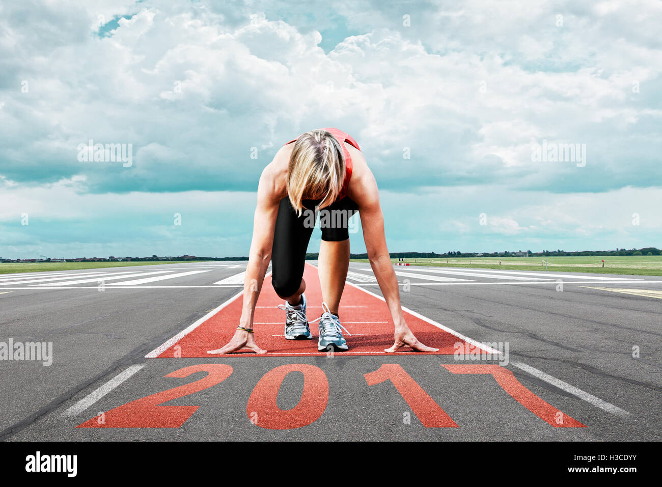Female runner waits for the 2017 start on an airport runway. In the foreground perspective view of the  date 2017. Stock Photo
