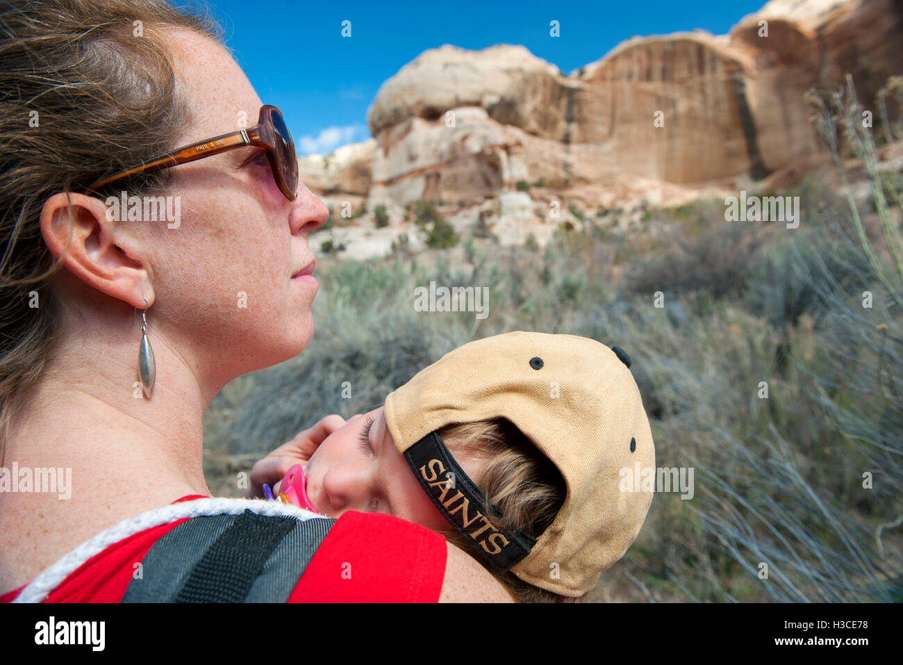 Mother hiking in nature, carrying sleeping son Stock Photo