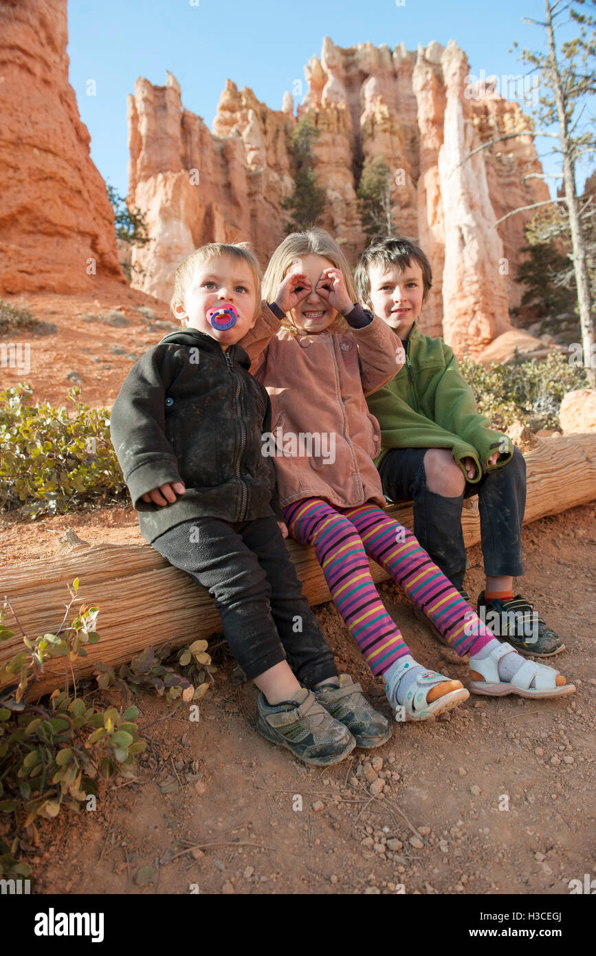 Children sitting on tree trunk at Bryce Canyon National Park, Utah, USA Stock Photo